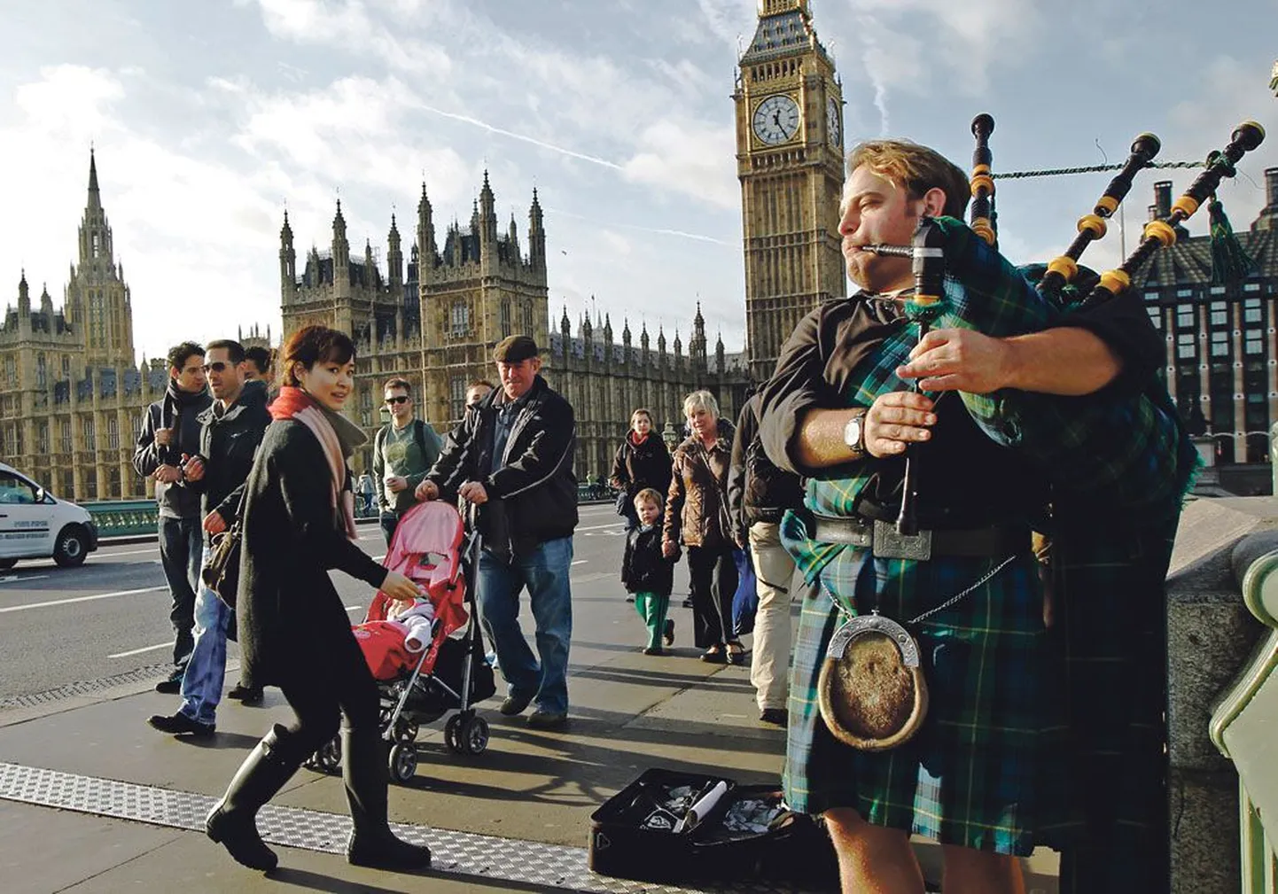 Уличный музыкант в национальном шотландском костюме играет на волынке возле Вестминстерского дворца в Лондоне.