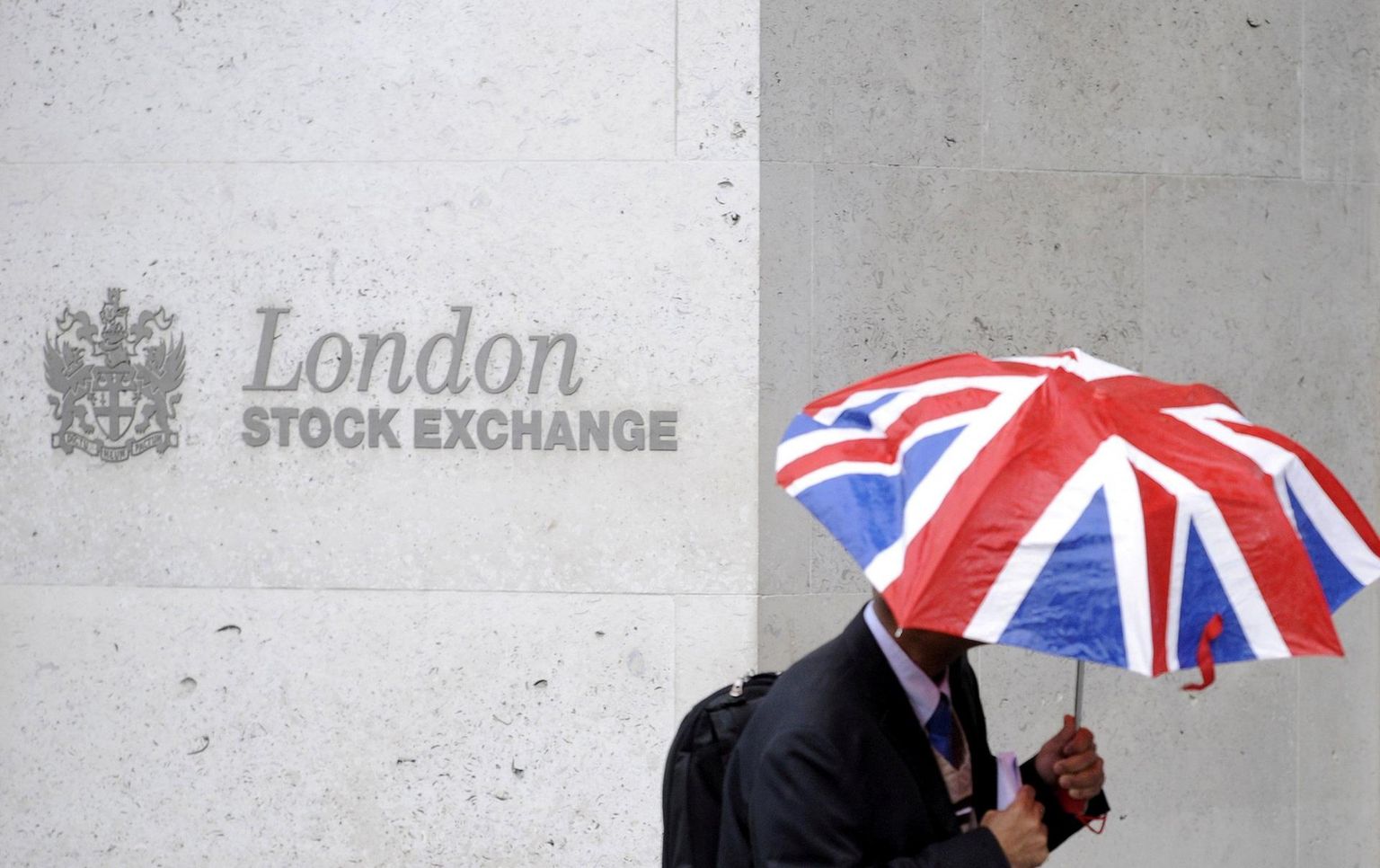 Briti lipu värvides vihmavarjuga mees Londoni börsi ees.