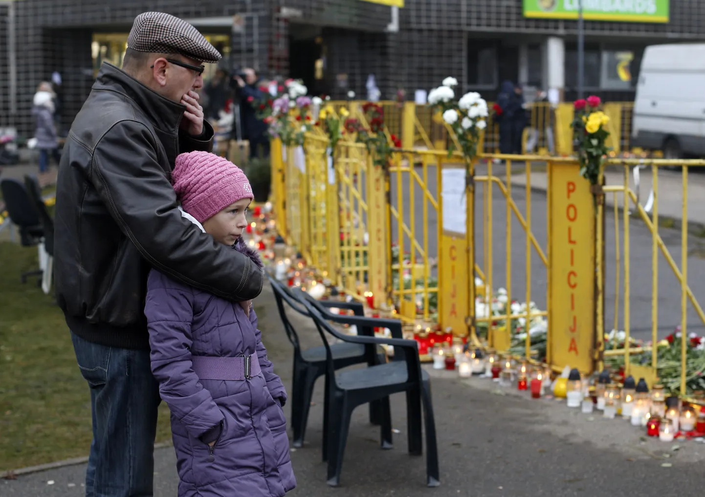 Inimesed seisavad Riia Maxima juures, kuhu on ohvrite mälestuseks toodud küünlaid ja lilli.