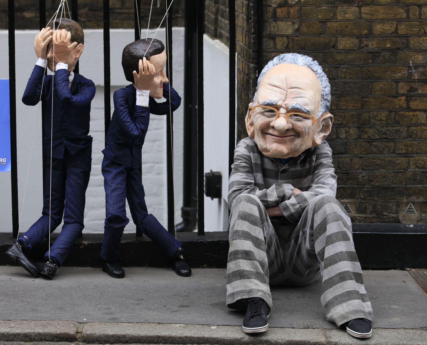 Rupert Murdochi peamaskis protestija ja marionettidena kujutatud peaminister David Cameroni nukud.