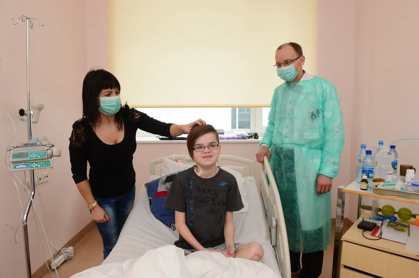 Uute kopsudega poiss Valter Kuld istub voodis. Ema Merilin Juhkam silub poja soengut, et pildistamine hästi välja kukuks. Paremal seisab kirurg Tanel Laisaar. Kõik, kes Valterit praegu külastavad, peavad kandma maski, kuna patsient on igasugusele infektsioonile veel ülitundlik.