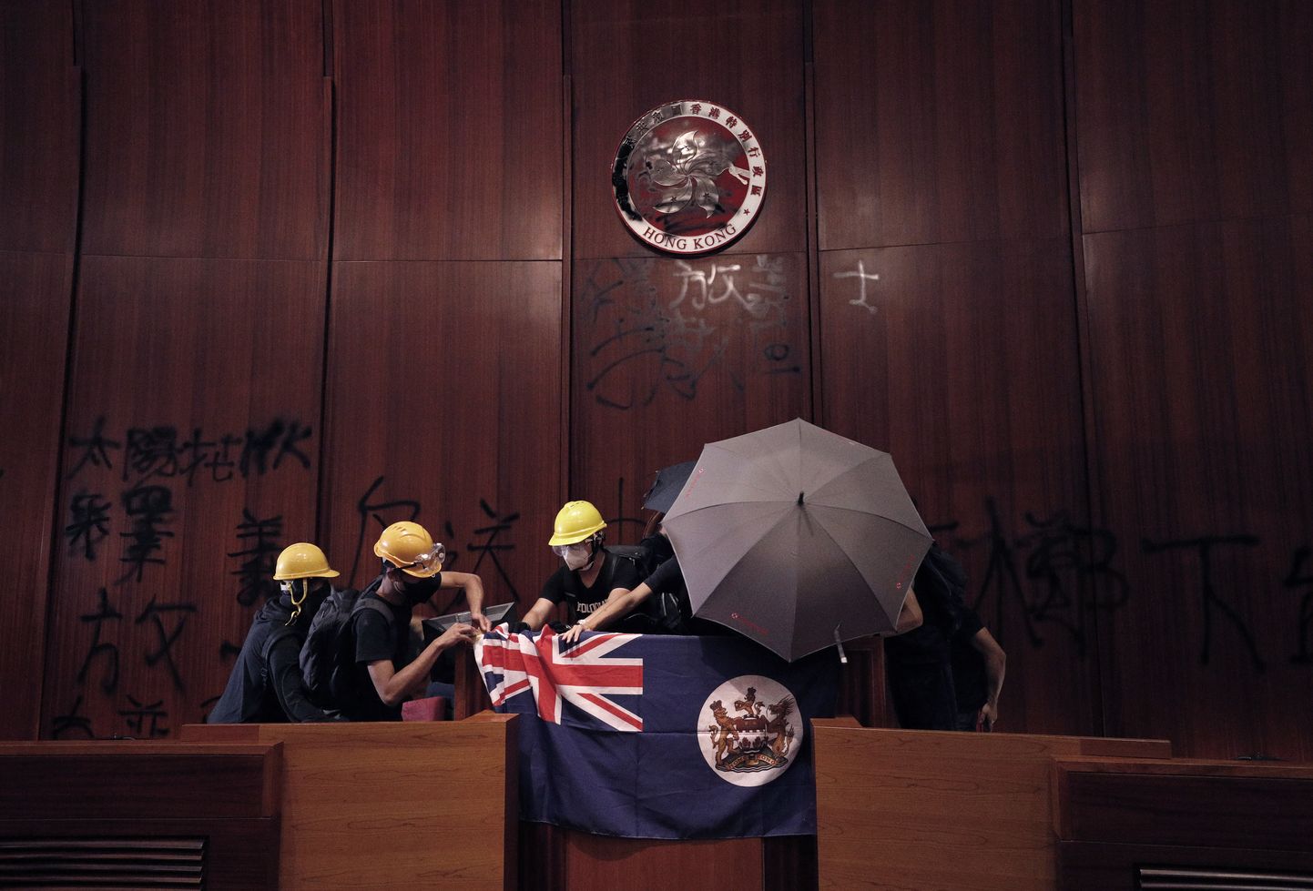 Hongkongi meeleavaldajad riputavad parlamendihoone auditooriumisse koloniaalaja lipu.