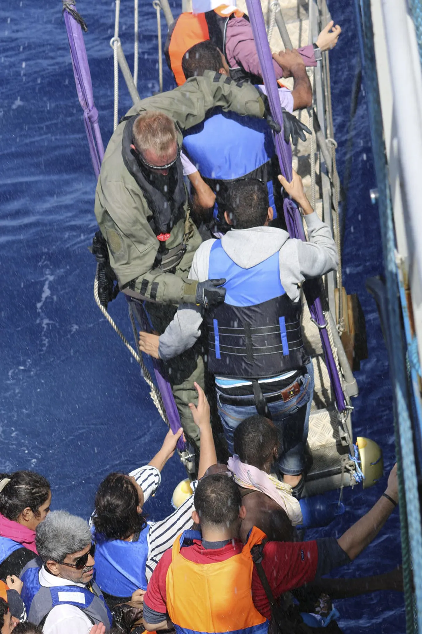 In this photo provided by the Swedish Coast Guard, migrants are boarding the ship Poseidon after being spotted in a fishing boat off  the Libyan coast Wednesday, Aug. 26, 2015. The Swedish ship Poseidon  rescued 439 survivors aboard a wooden ship, discovering in the hull the corpses of 51 migrants who died,  probably of asphyxiation, making the dangerous Mediterranean crossing in hopes of reaching Europe. (Swedish Coast Guard via AP Photo) MANDATORY CREDIT