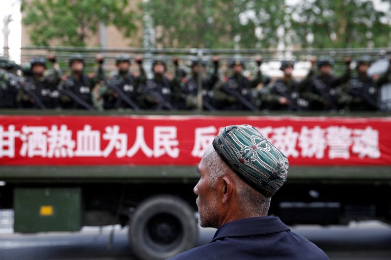 Uiguur jälgimas sõjaväelasi vedavat veokit Hiinas Xinjiangis.