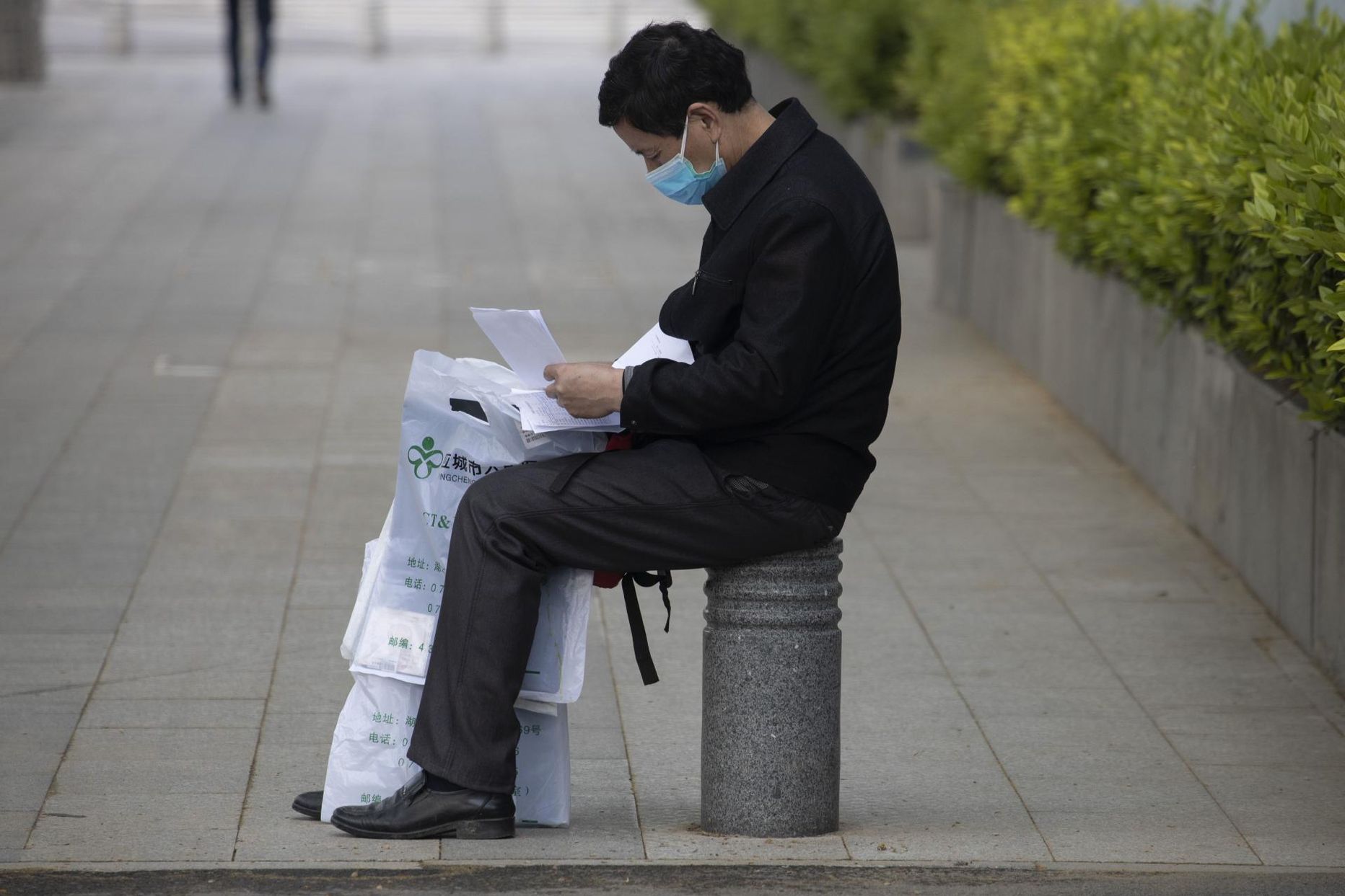 Haiguslooga tutvuv mees istub Wuhani haigla lähistel tänaval.