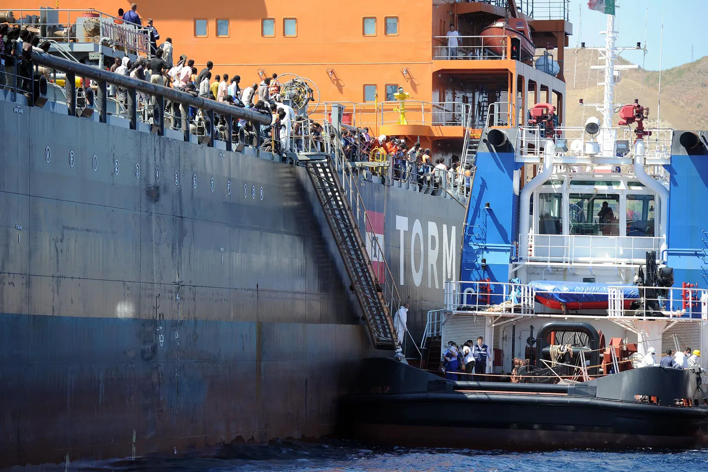 Uppumissurmast päästetud paadipõgenikud lahkuvad tankeri Torm Lotte pardalt puksiirile, et Itaalias maale pääseda.