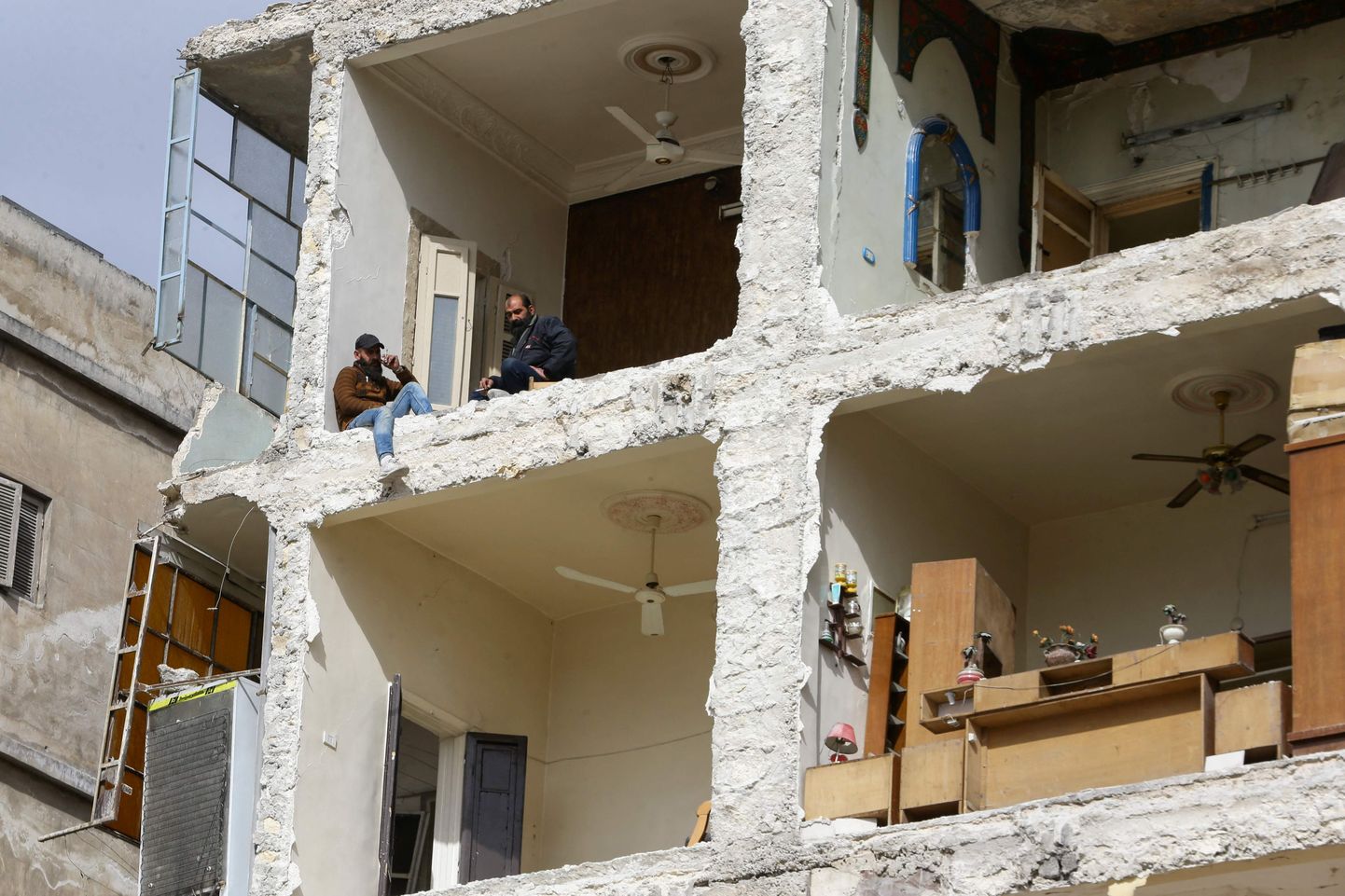 Kohalikud elanikud istuvad oma purustatud kodus Süürias Aleppos maavärinas kahjustada saanud hoones.