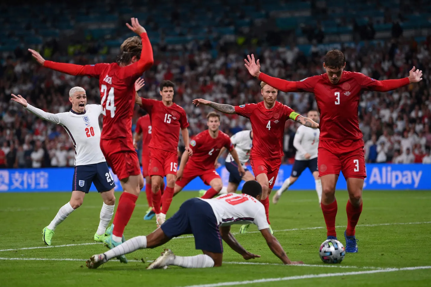 Inglise ründaja Raheem Sterling kukkumas EMi poolfinaalis. Punastes särkides taanlased üritavad näidata, et nad ei puutunud Sterlingit. Sellest hoolimata määras kohtunik Danny Makkelie inglastele penalti