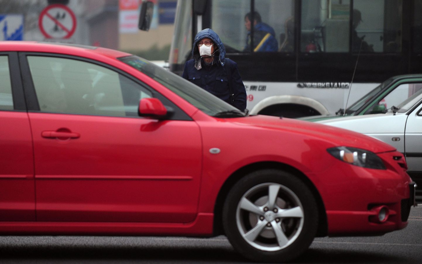 Maskiga jalakäija sudusel Pekingi tänaval. Hiinas on selle aasta 11 kuuga müüdud eelmise aastaga võrreldes poole rohkem sõiduautosid.