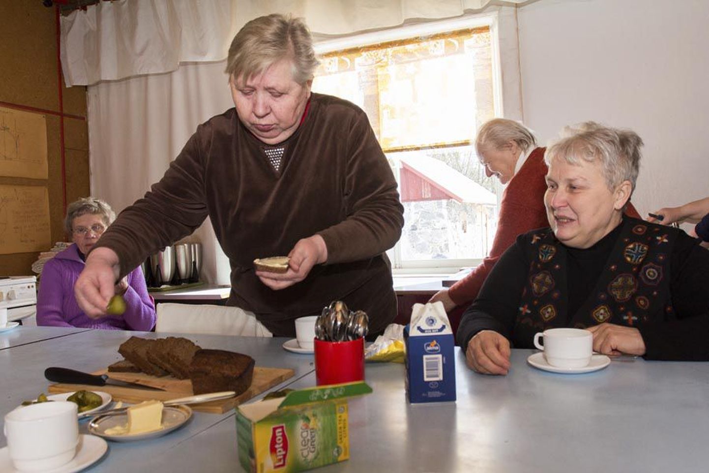 Koksvere maanaiste seltsi liikmed Aili Almar (vasakul) ja Tiina Leis omavalmistatud leiba mekkimas. Tagaplaanil on Malle Laan ja Elvi Soolo.