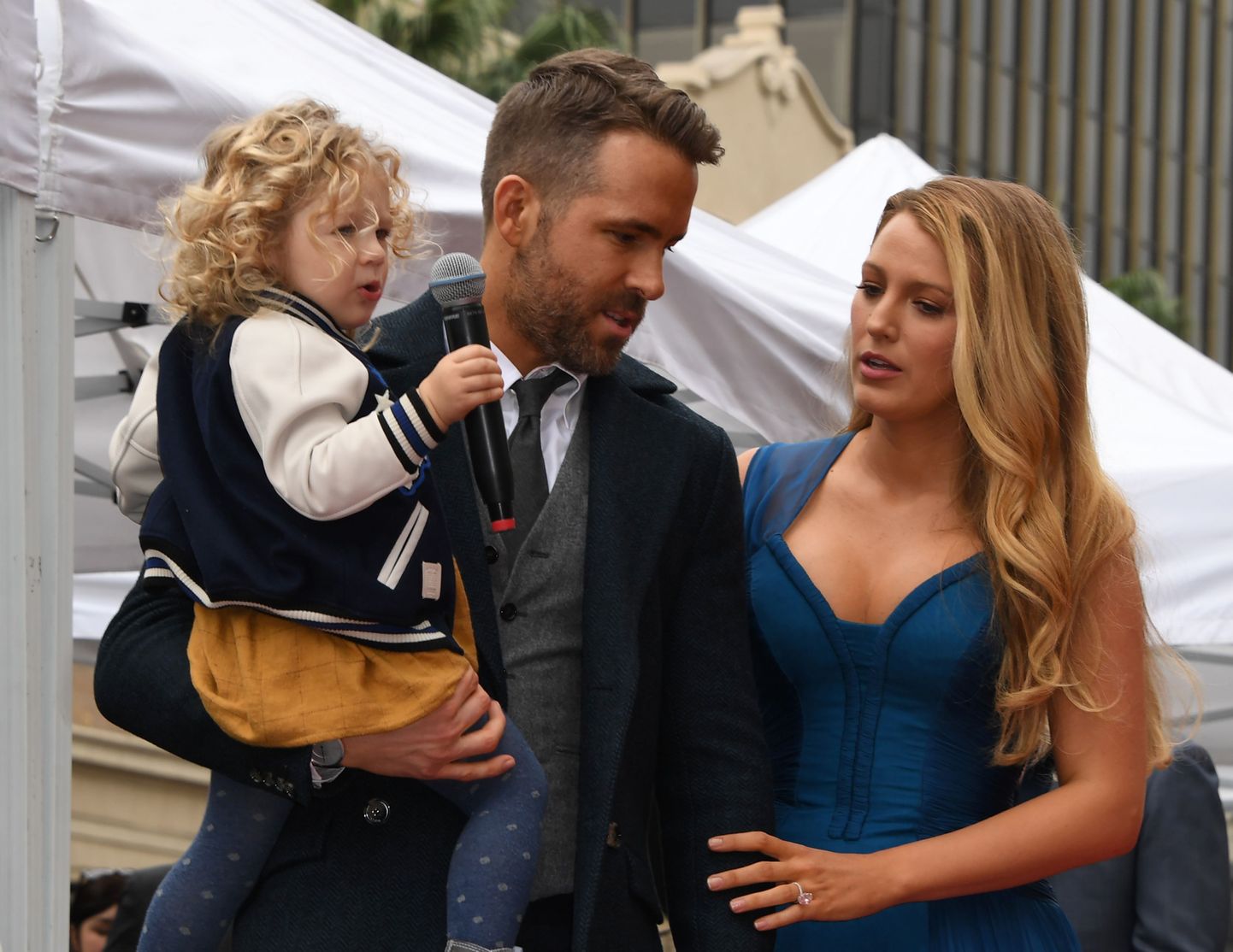 Actor Ryan Reynolds holds his daughter James as his wife Blake Lively looks on the Deadpool actor