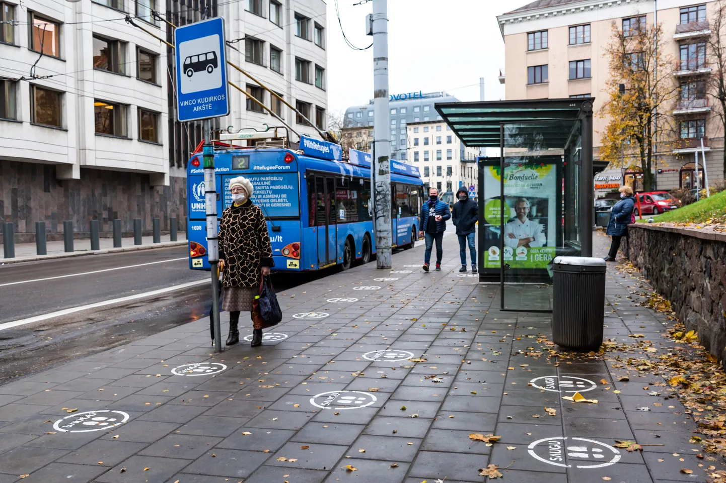 Sabiedriskā transporta pietura Lietuvas galvaspilsētā Viļņā. Uz bruģa uzzīmētas pēdas, mudinot ievērot 2 metru distanci. Ilustratīvs attēls.