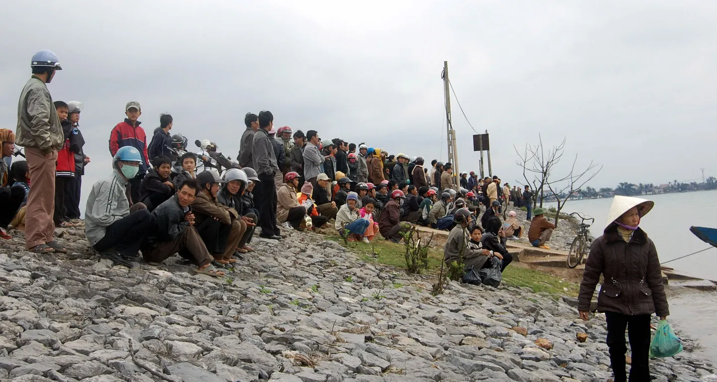 Locals gather near the scene of a river boat accident in Quang Trach district, a central province of Quang Binh on January 25, 2009. At least 40 people have drowned in the accident in Vietnam, when a crowded vessel sank while taking people to a market for lunar New Year shopping, a senior provincial official said. The wooden boat sank amid strong currents and cold winds 20 metres (65 feet) from shore on the Gianh river in central Quang Binh province when passengers scrambled to get off before it reached the pier, the official said. AFP PHOTO/TTo
