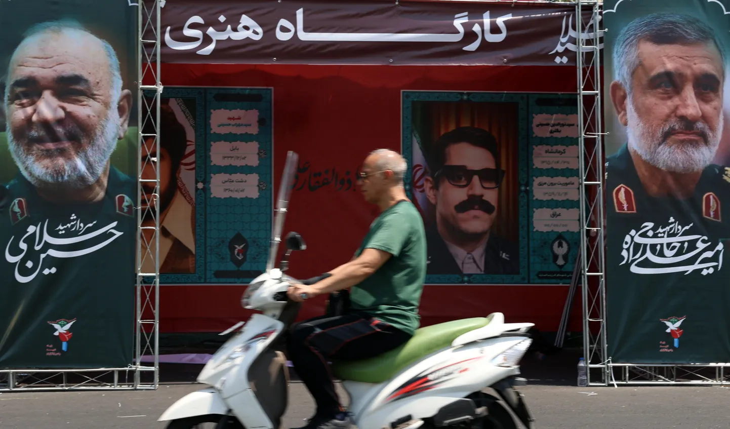 Irānis brauc garām plakātiem ar Islāma revolucionāro gvardu korpusa (IRGC) virspavēlnieka Hosseina Salami un IRGC Aerokosmisko spēku komandiera Amira Ali Hadžizadeha portretiem Teherānā, Irānā, 2025. gada 14. jūnijā.