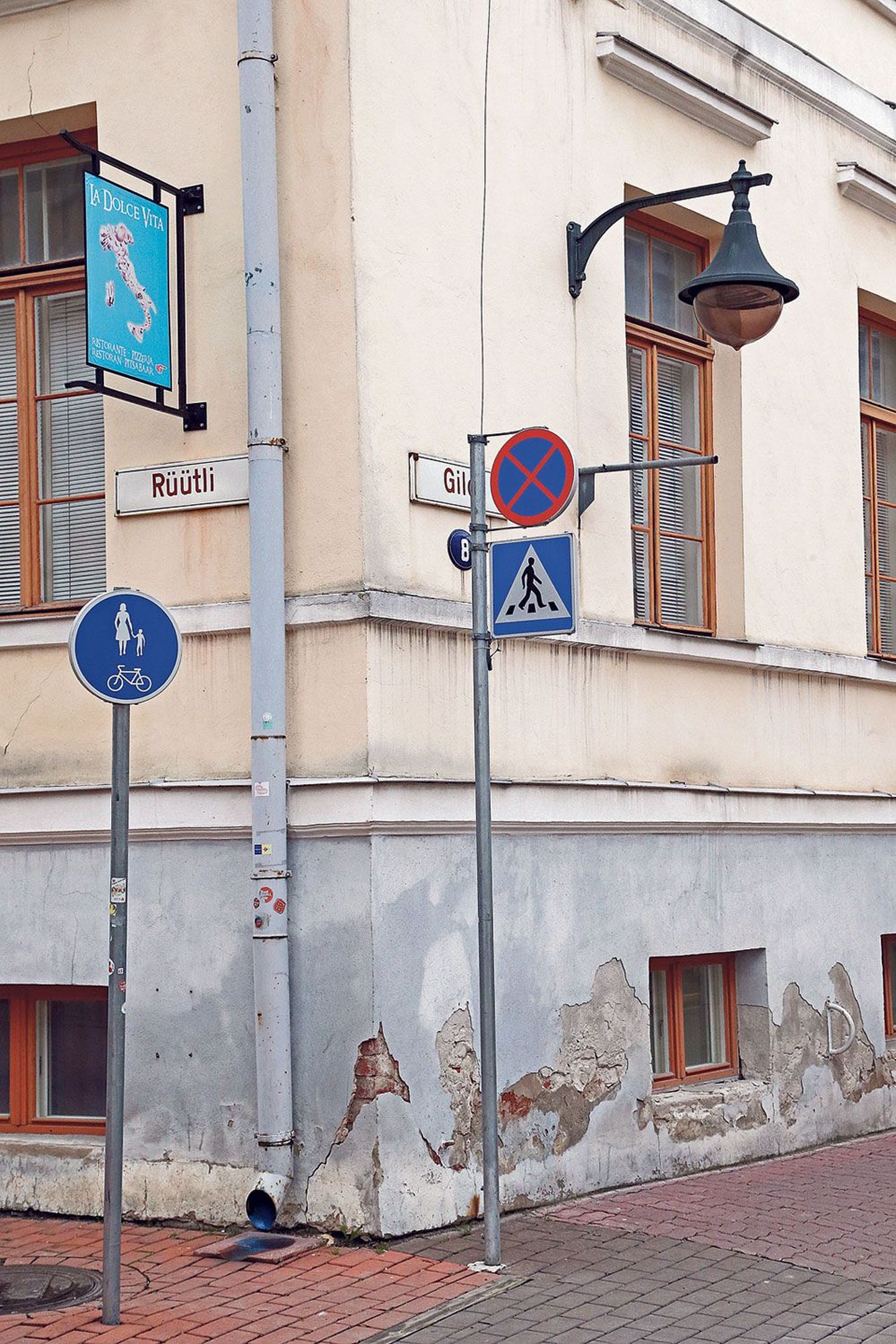 Tartu linnapolikliiniku seinal on restoranireklaam ja vana liiklusmärgikandur.