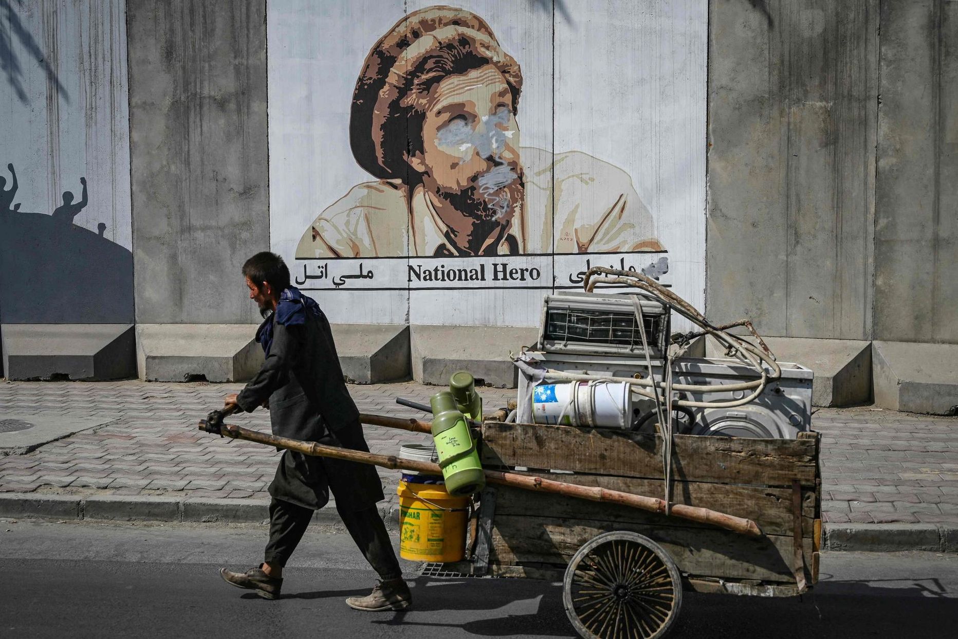 Tööline möödub Kabulis 90ndatel aastatel Talibani vastu võidelnud Ahmad Shah Massoudi soditud portreest. 