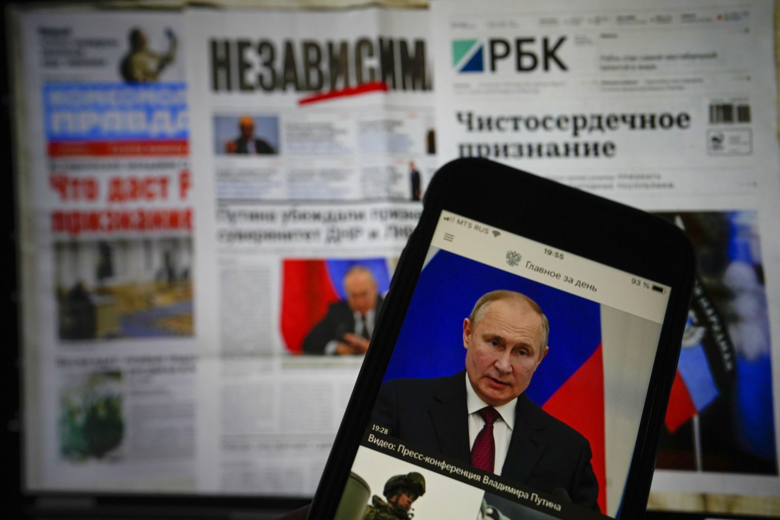Российские газеты и россиянин, читающий новости на своем iPhone. Фото сделано 22 февраля 2022 г. Два дня спустя, 24 февраля 2022 г., российские войска вторглись в Украину.