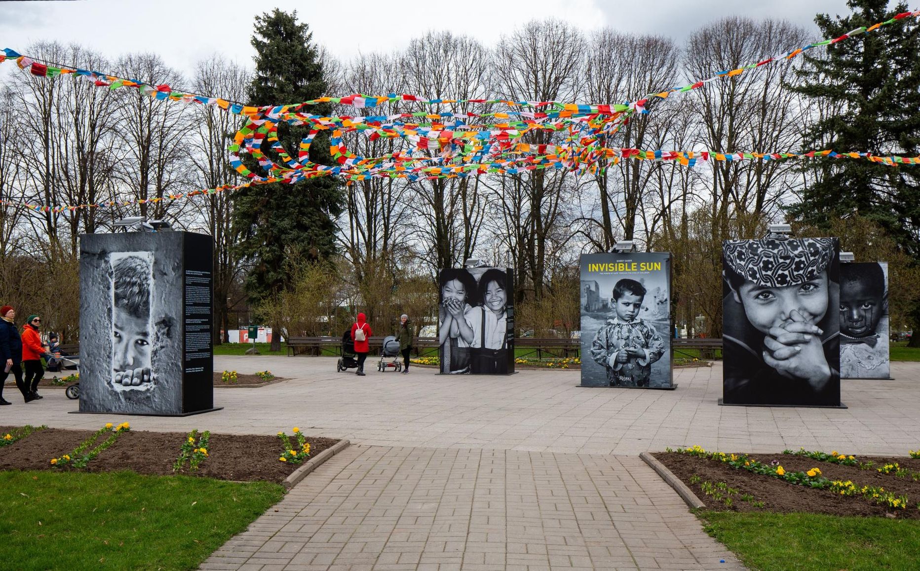 Tartu kesklinna pargis lehvivad näituse fotode ja tekstide kohal Tiibeti palvelipud.