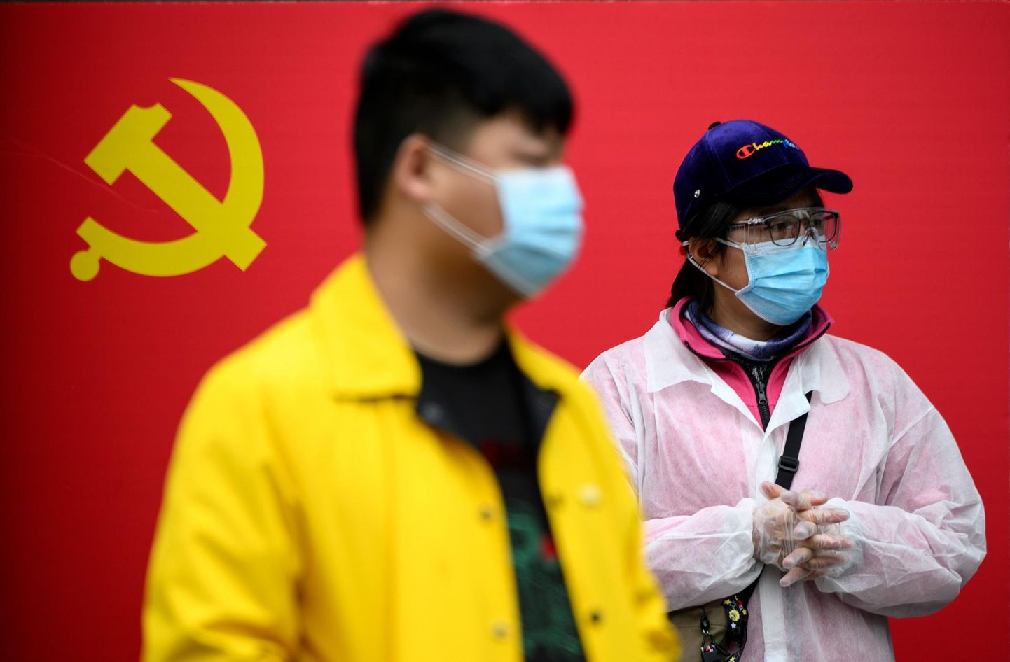 Näomaski kandvad inimesed Wuhanis Hiina Kommunistliku Partei lipu ees.