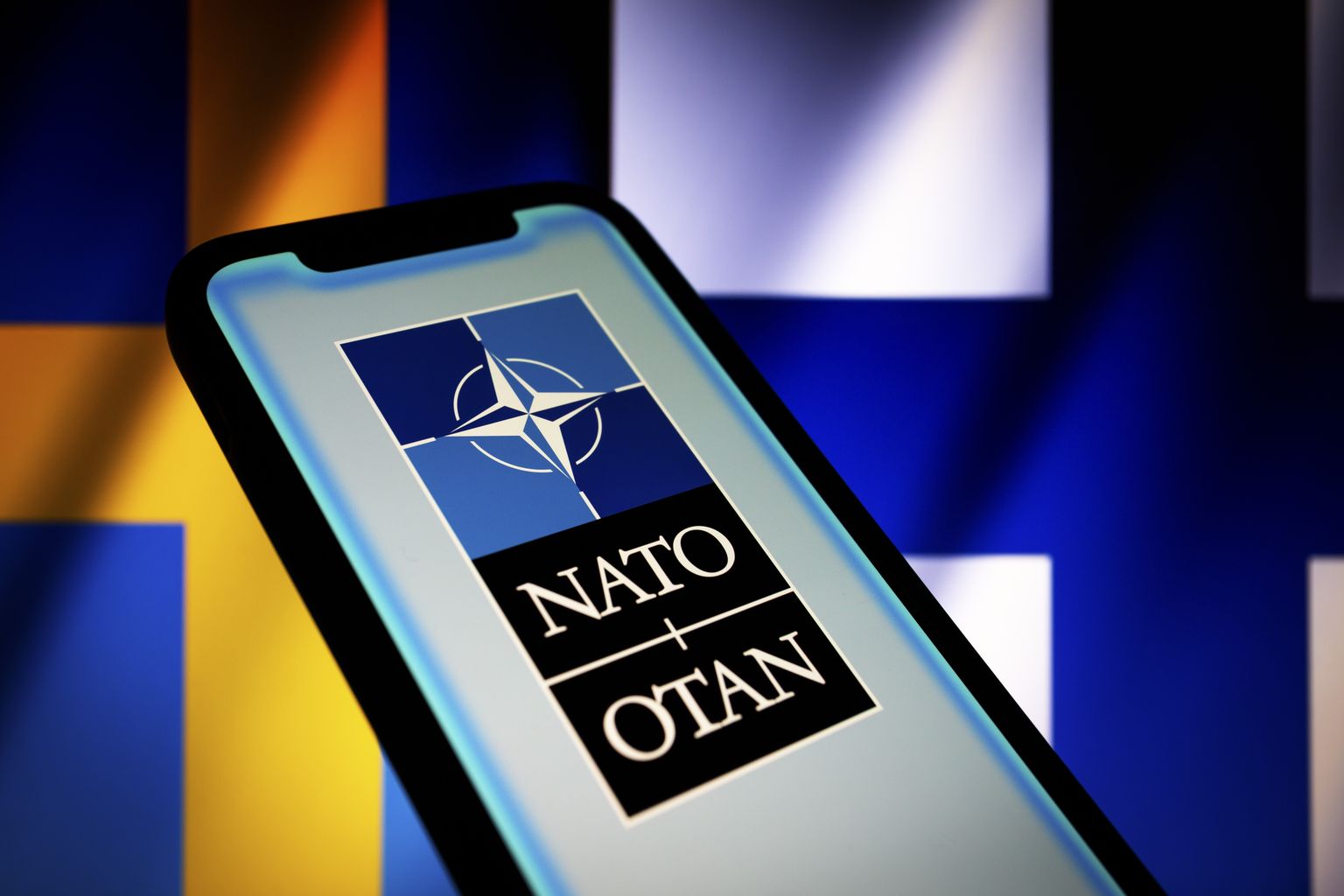 NATO logo, taustal on Rootsi ja Soome lipp