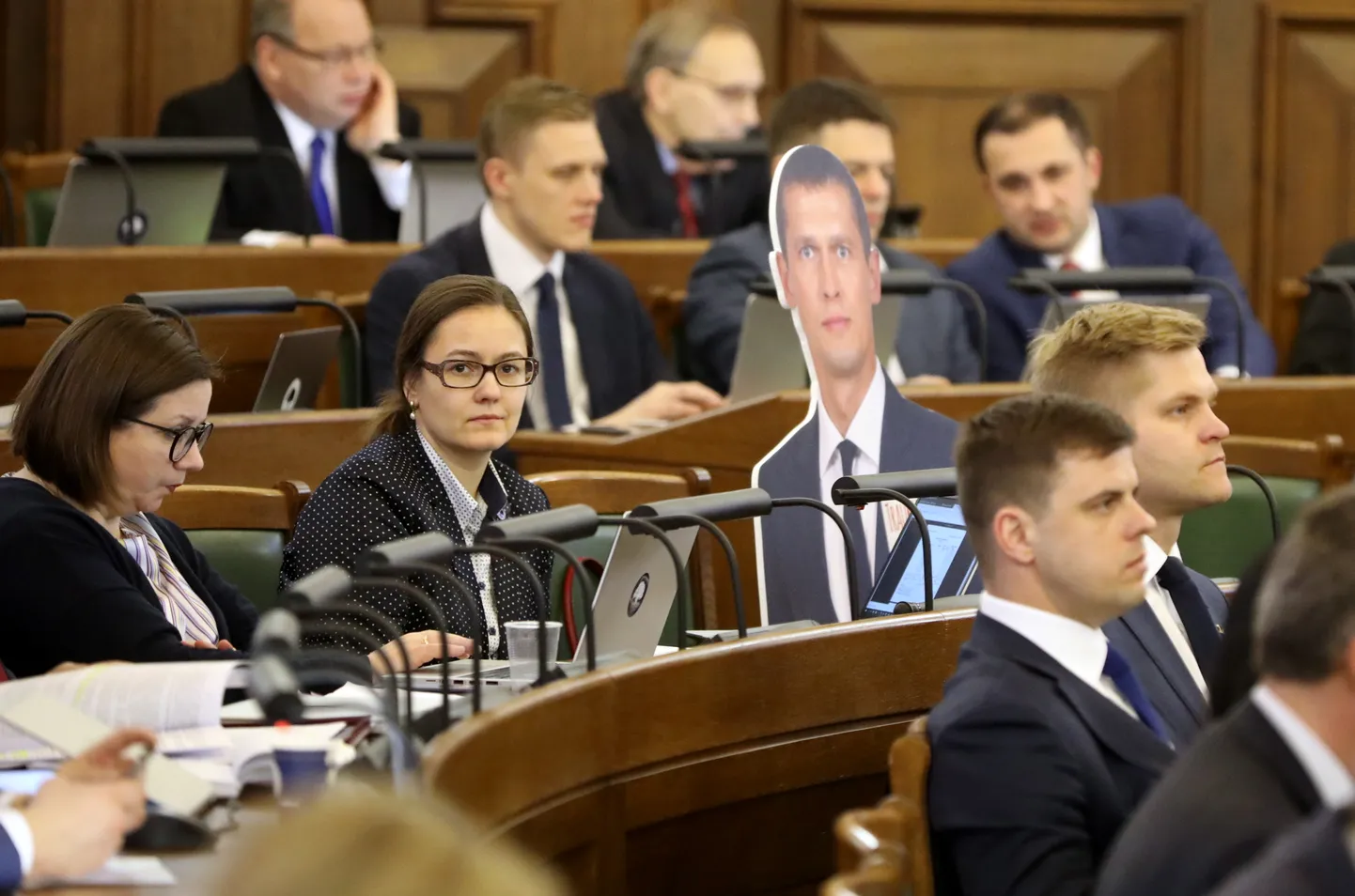 Saeimas deputātes Evita Zālīte-Grosa (no kreisās), Linda Ozola un kriminālvajāšanai izdotā deputāta Jura Juraša fotogrāfija uz kartona Saeimas sēdes laikā, kurā lemj par 2019. gada valsts budžeta projektu.