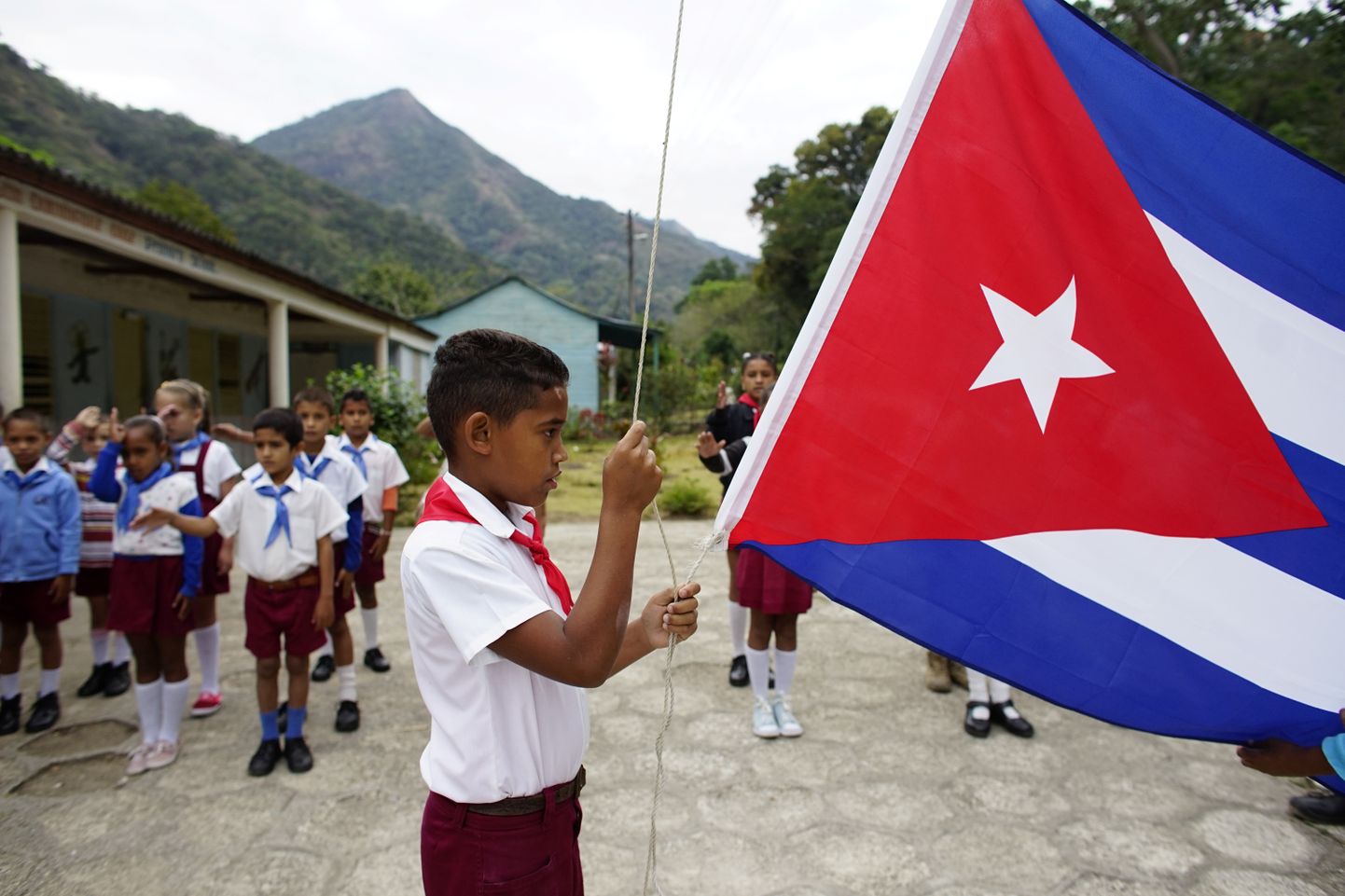Koolipoiss riiklikul pühal Kuuba riigilippu heiskamas.