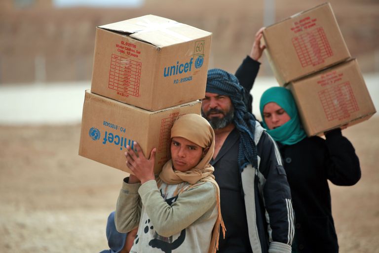Kodust lahkuma sunnitud süürlased kannavad abikaste UNIFECi jagatud toodetega.
