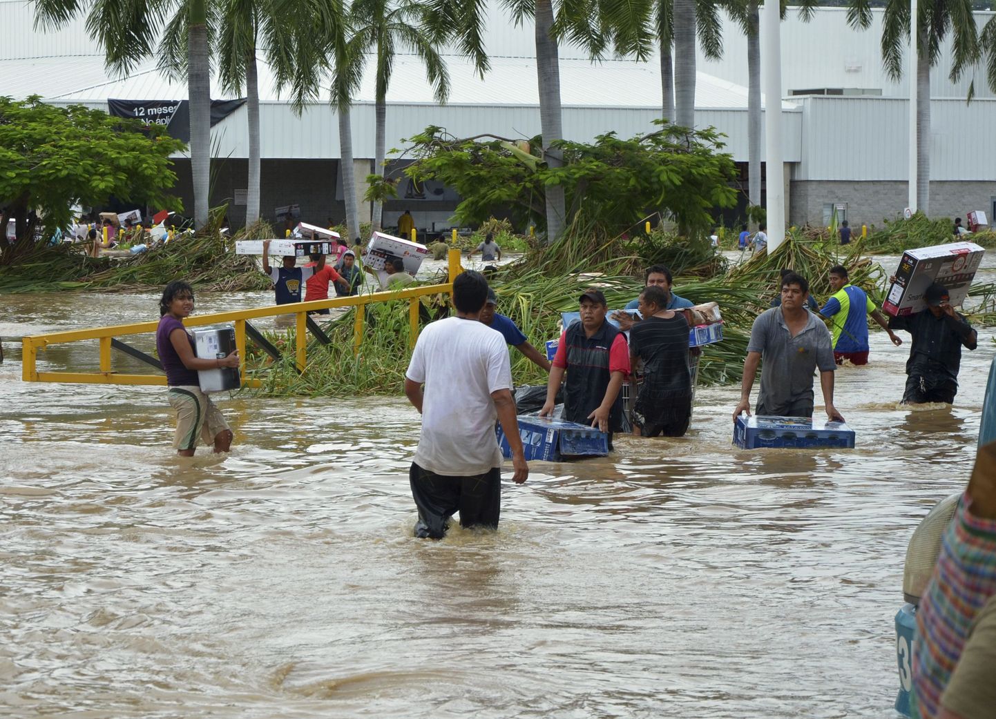 Inimesed kahlavad läbi suurvee, kandes käes Acapulco ühest kaubanduskeskusest ostetud kaupu.