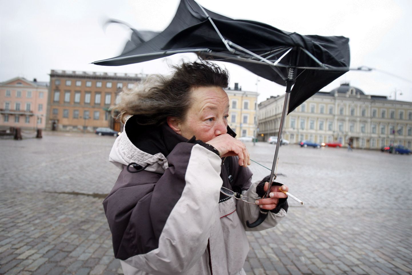 Helsingi turuplatsil tuulega võitlev naisterahvas.