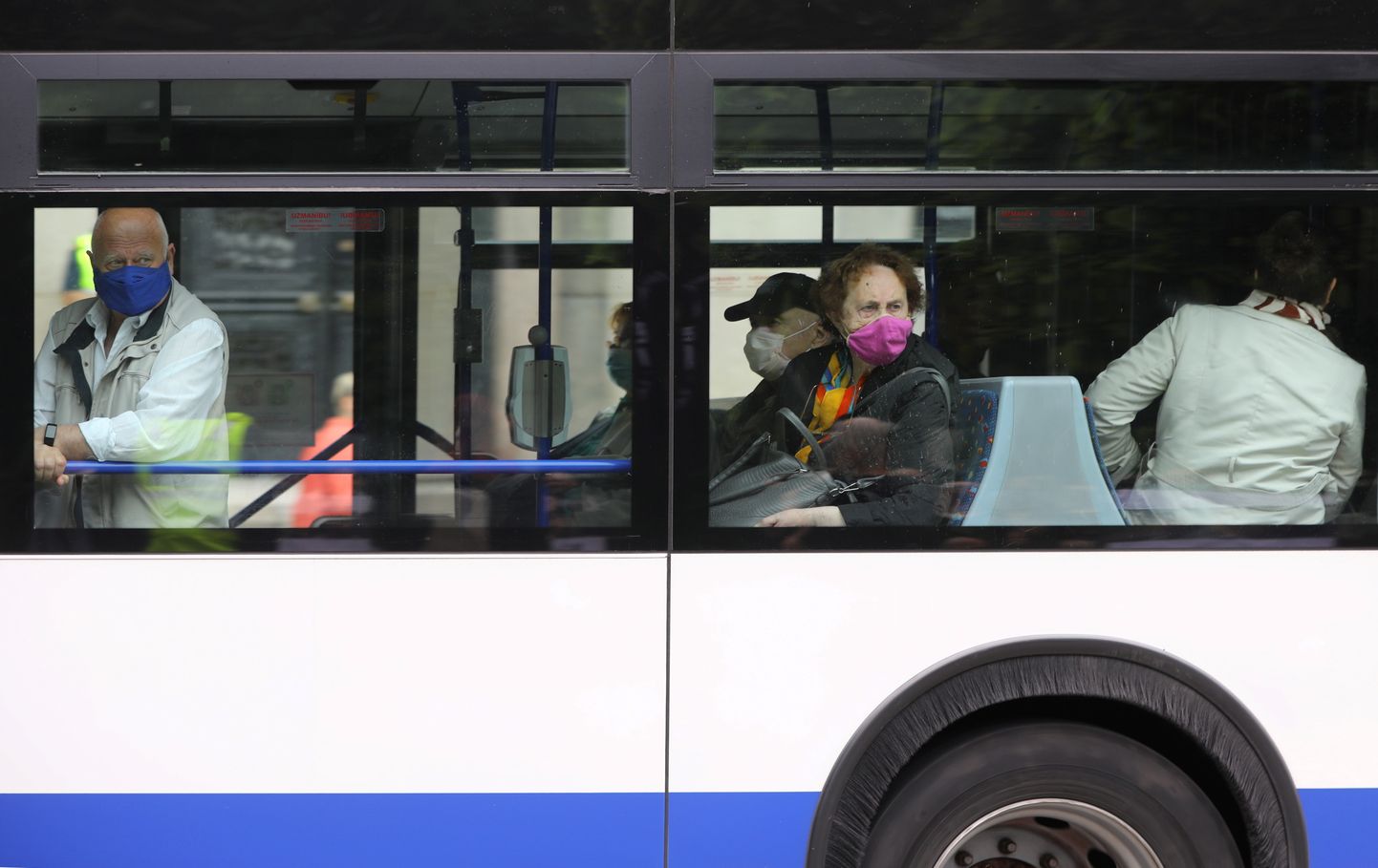 Cilvēki sejas aizsargmaskās sabiedriskajā transportā.