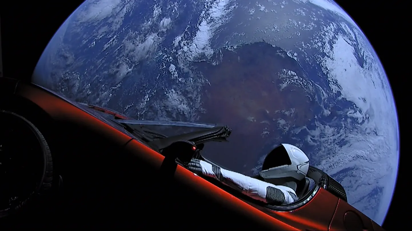 Elon Muski Tesla Roadster Maa taustal, SpaceXi kosmoseülikonda kandev mannekeen juhiistmel. Kaamera asub välise varda otsas.