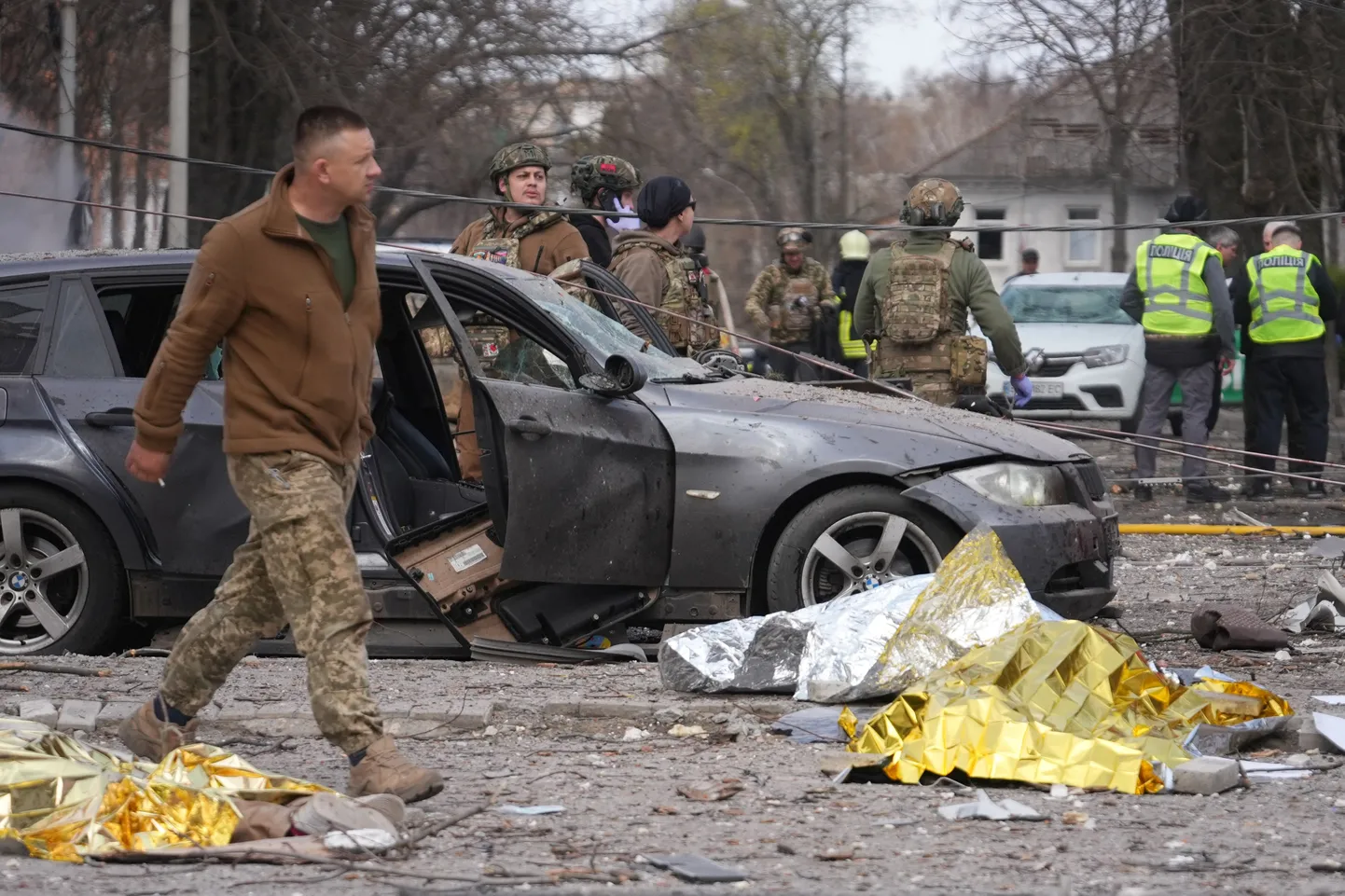 Apklāti upuru ķermeņi guļ uz ceļa, kamēr Ukrainas tiesībsargājošo iestāžu darbinieki strādā raķešu uzbrukuma vietā Sumos, Ukrainas ziemeļaustrumos, 2025. gada 13. aprīlī, Krievijas iebrukuma Ukrainā laikā.