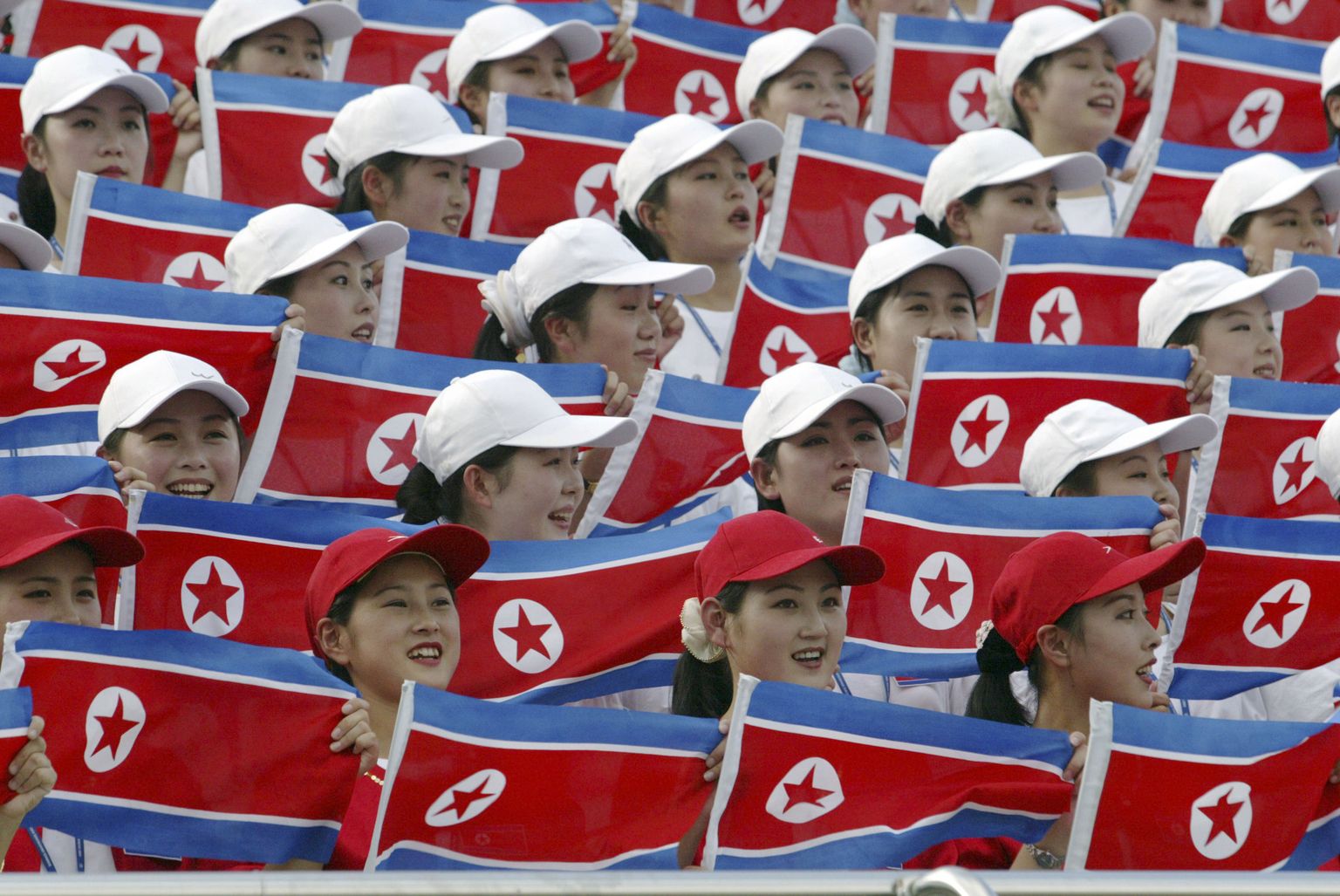 FILE - In this Aug. 28, 2003 file photo, North Korean women hold national flags to cheer at the Daegu Universiade Games in Daegu, South Korea. Sports ties between the rival Koreas often mirror their rocky political ties. North Korea participated in the University Games in Daegu, South Korea in 2003, and its athletes walked again with South Korean counterparts at the opening and closing ceremonies. (AP Photo/Lee Jin-man, File)
