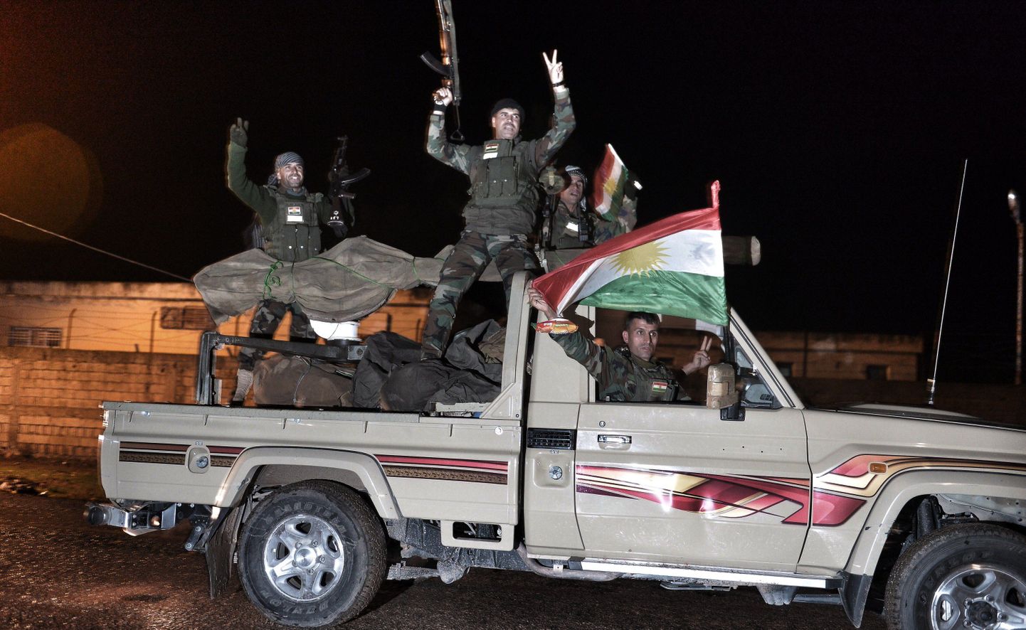 Kurdi pešmerga sõdalased lehvitavad oma lippu ja vehivad relvadega Kobane suunas sõites.
