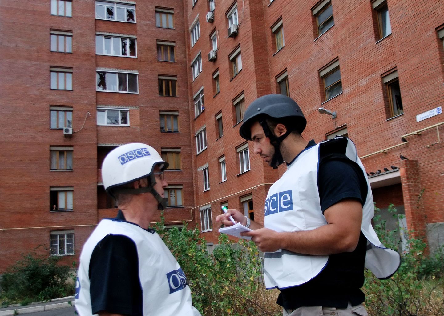 OSCE vaatlejad Donetskis sõjategevuses kõvasti kannatada saanud kortermaja ees.