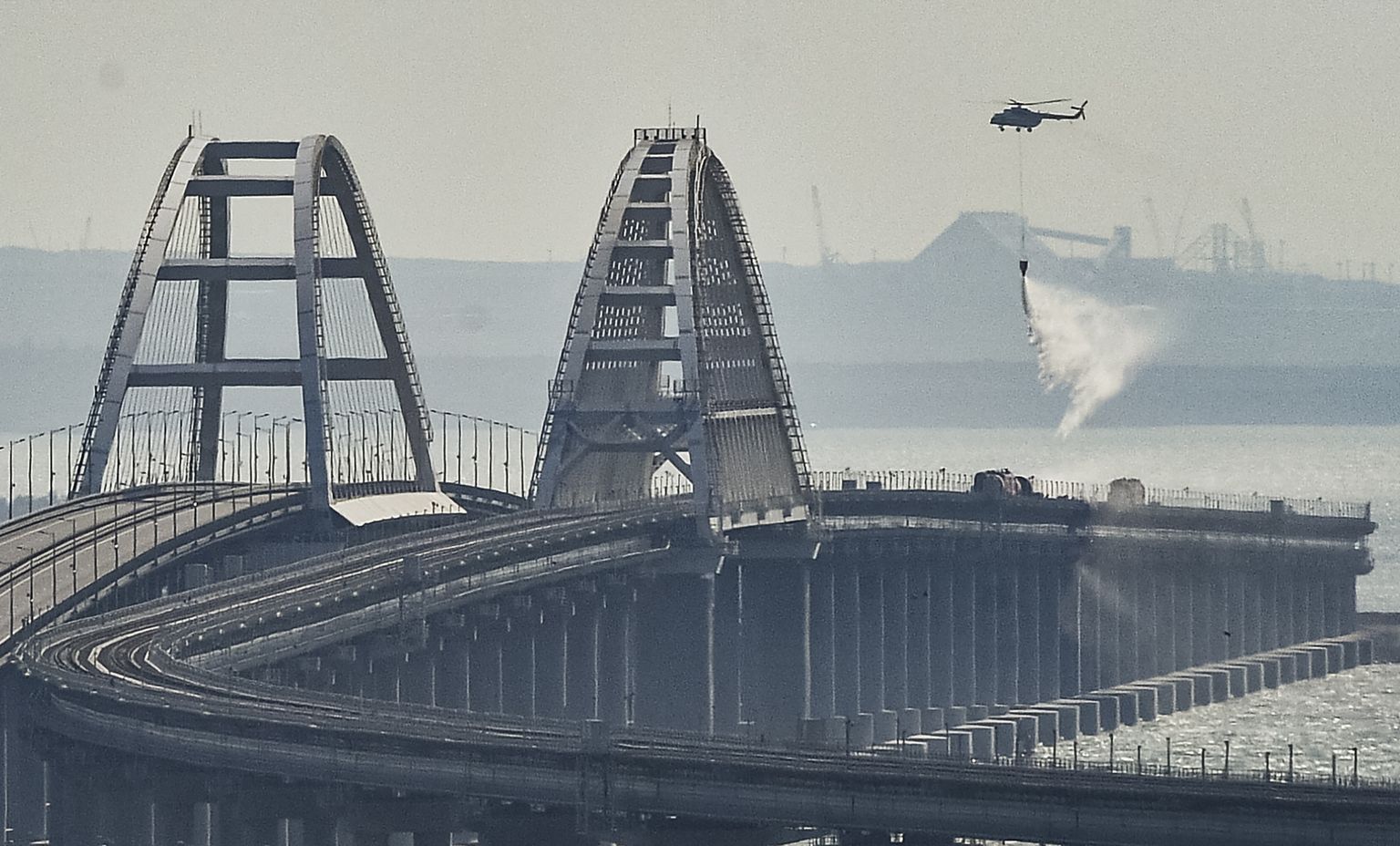 Пожарный вертолет над обрушившемся участком моста через Керченский пролив в Крыму, 08 октября 2022 года.