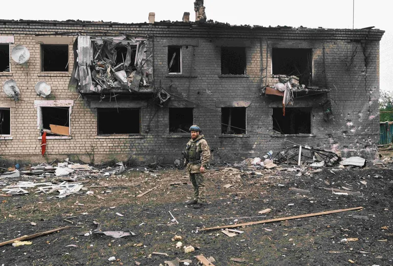 Украинский военный на фоне обгоревшего и разрушенного дома.