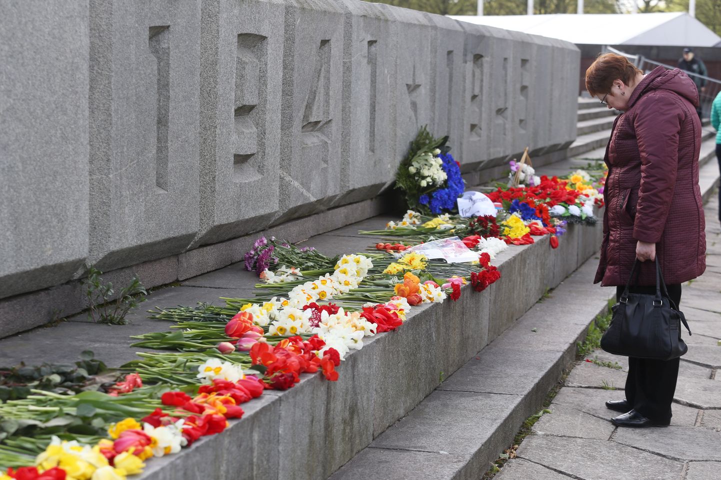 Sieviete noliek ziedus biedrības "9.maijs" rīkotajā Otrā pasaules kara upuru piemiņas dienas pasākumā Uzvaras parkā.