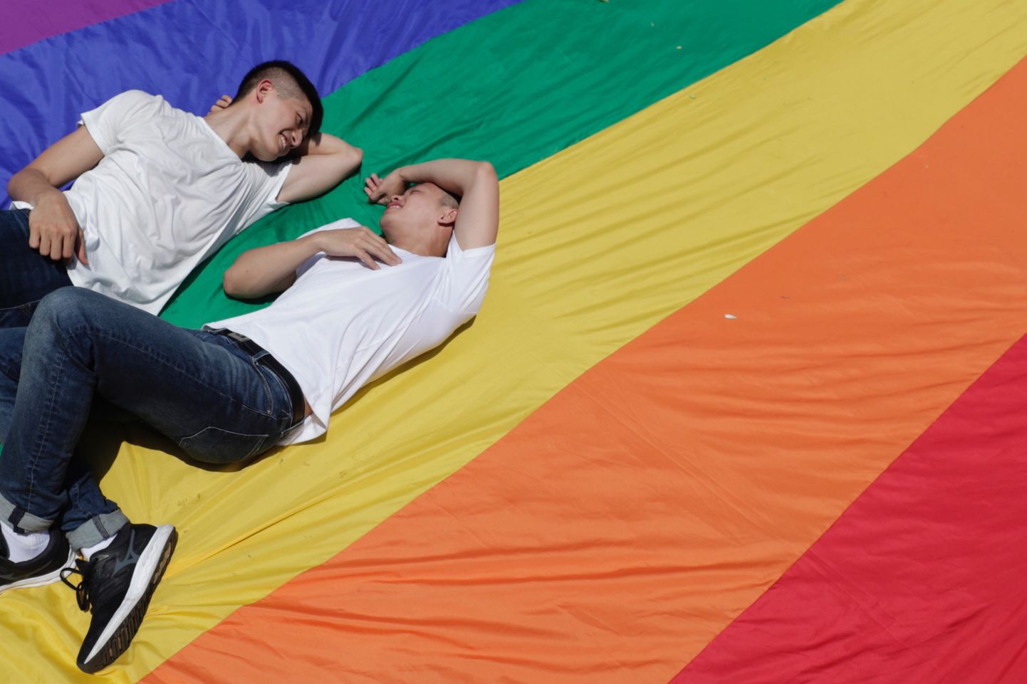 Молодые люди на фоне флага ЛГБТ-сообщества. Фото иллюстративное.