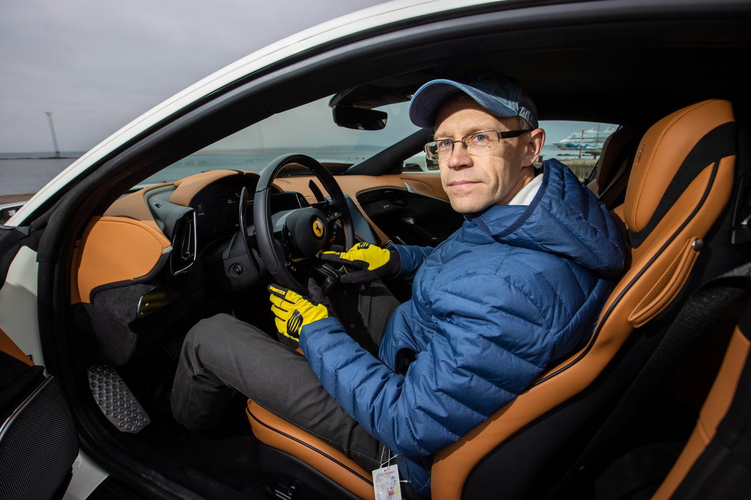 Ajakirjanik Priit Pullerits osutamas nimetissõrmega Ferrari Roma roolil kohale, kus asub käivitusnupp.