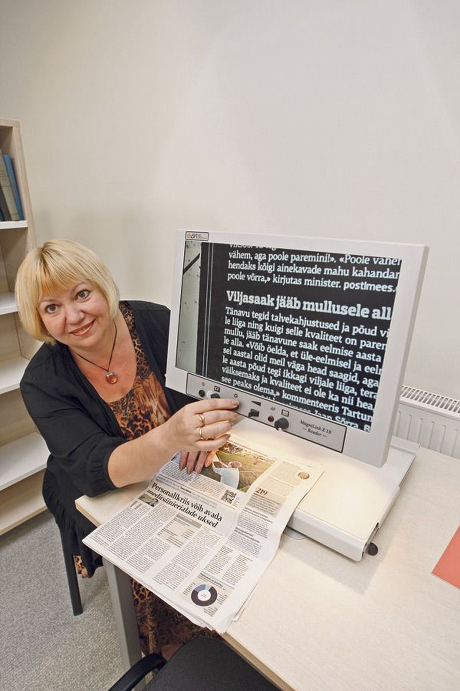 Olga Einasto näitab, milline paistab ajaleheuudis 46-kordse suurendusega lugemisteleri ekraanilt.