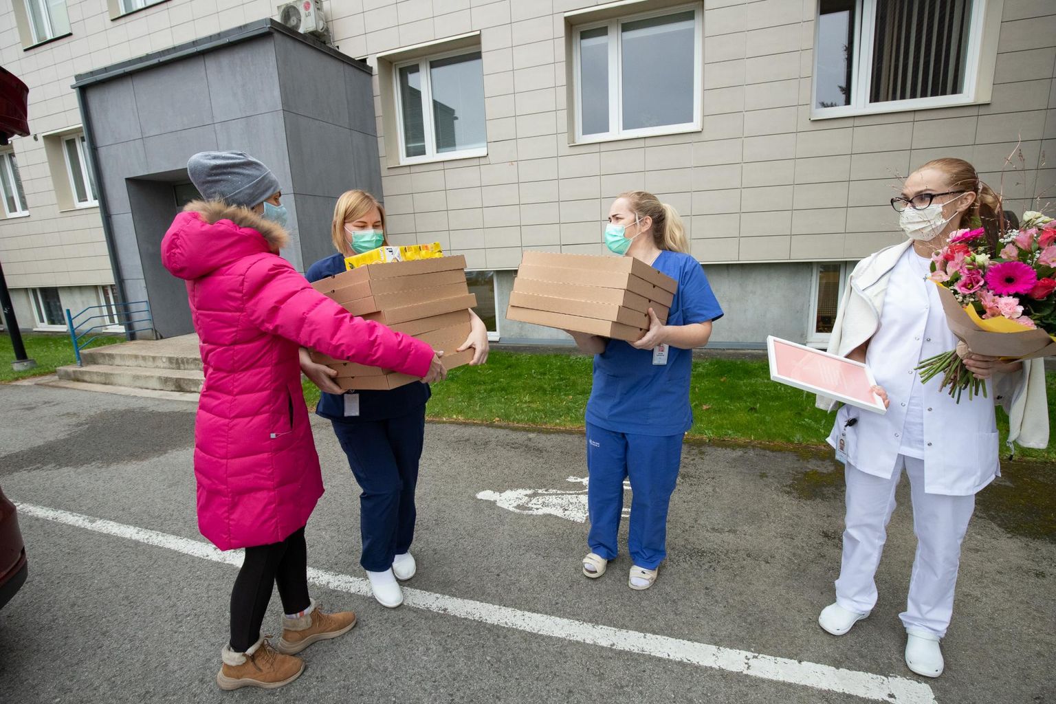 Piret Kaarlõp (roosas jopes) annab üle pitsad Rakvere haigla töötajatele.