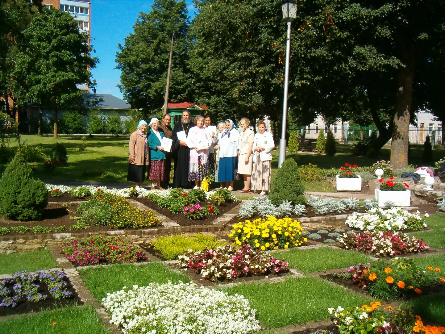 Служители церкви Казанской иконы Божьей матери и их помощники в саду у здания церкви.