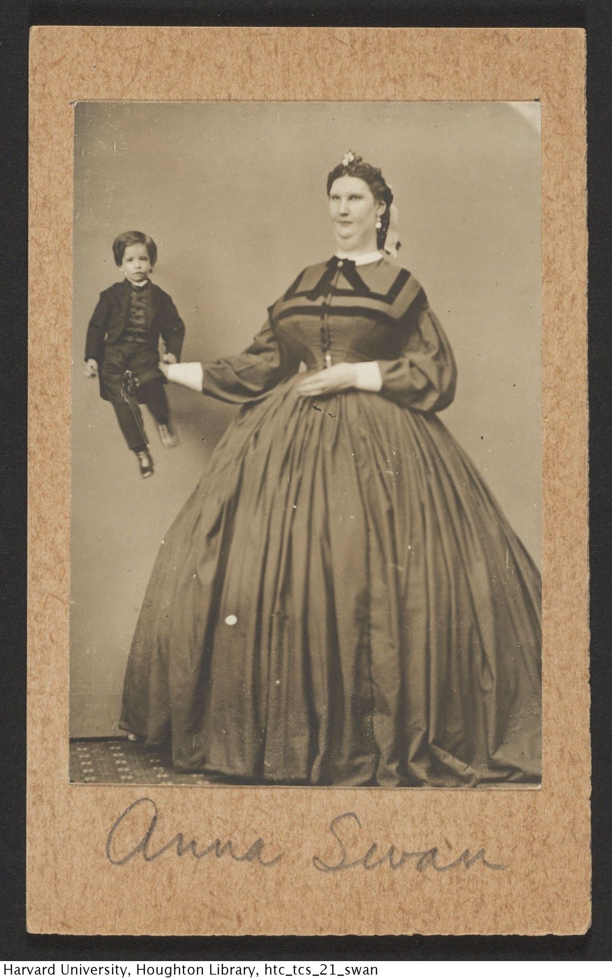 Hiiglasekasvu Anna Swan oma pikkuse illustreerimiseks poseerimas koos tavalist kasvu väikelapsega.