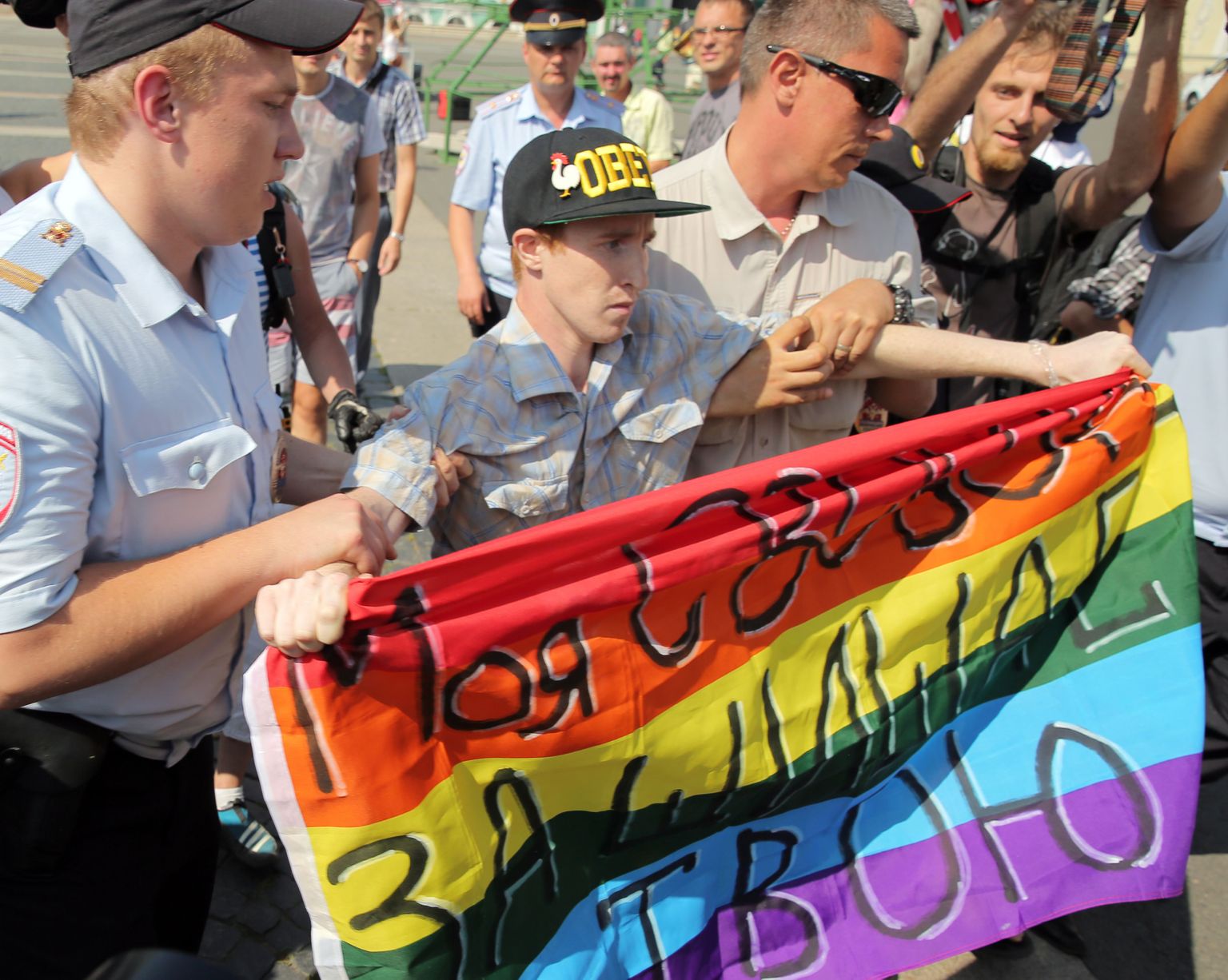 Politseinikud toimetavad ära LGBT aktivisti Kirill Kaluginit pärast tema üheinimese protesti Venemaal, väljakul. Lipul on kirjas «Minu vabadus kaitseb sinu oma.»