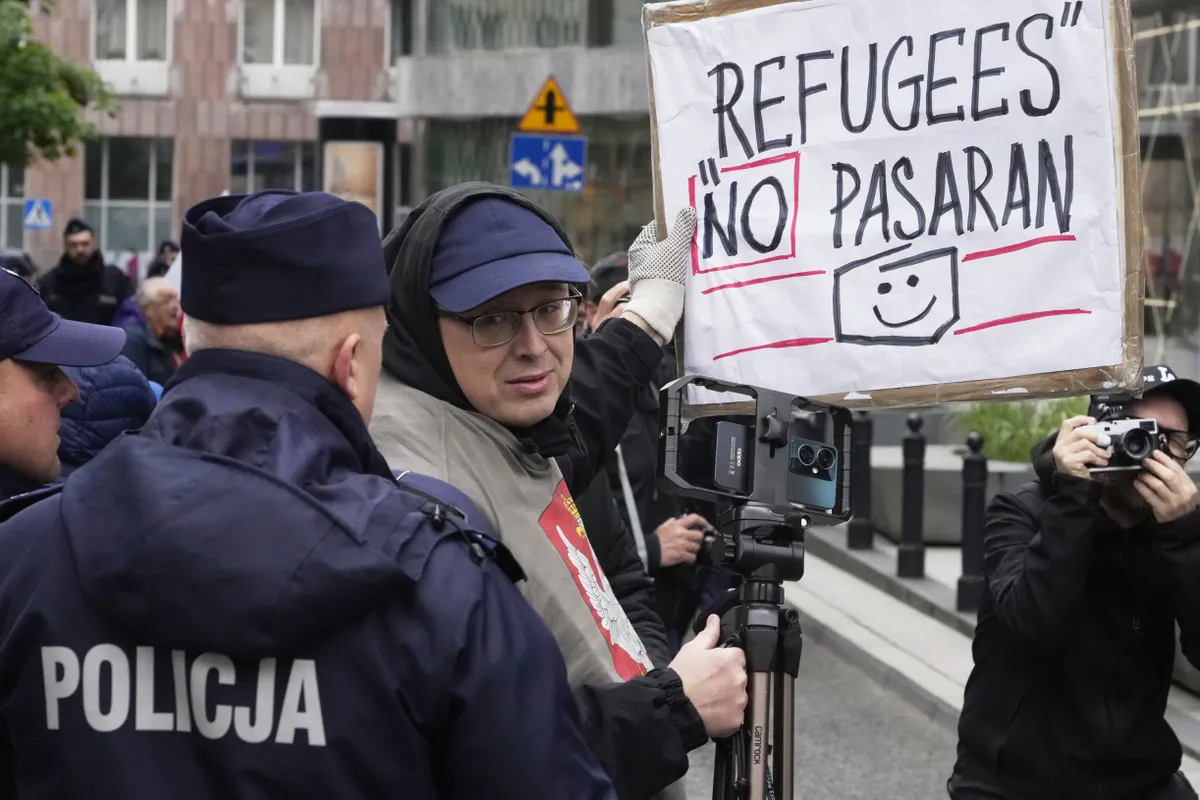 A man holds a poster that says "Refugees NO pasaran" in Warsaw, Poland, Saturday, May 10, 2025.