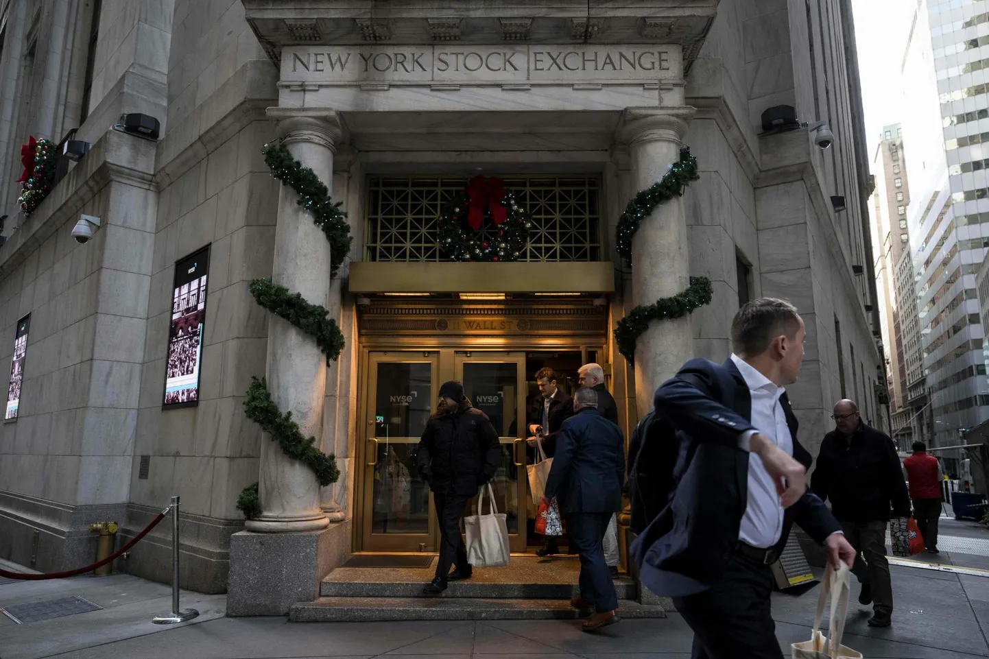 Inimesed jalutamas Wall Streetil New Yorgi börsi hoone esiuksest sisse-välja.