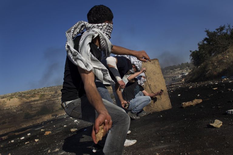 Палестинцы забрасывают камнями израильских солдат.