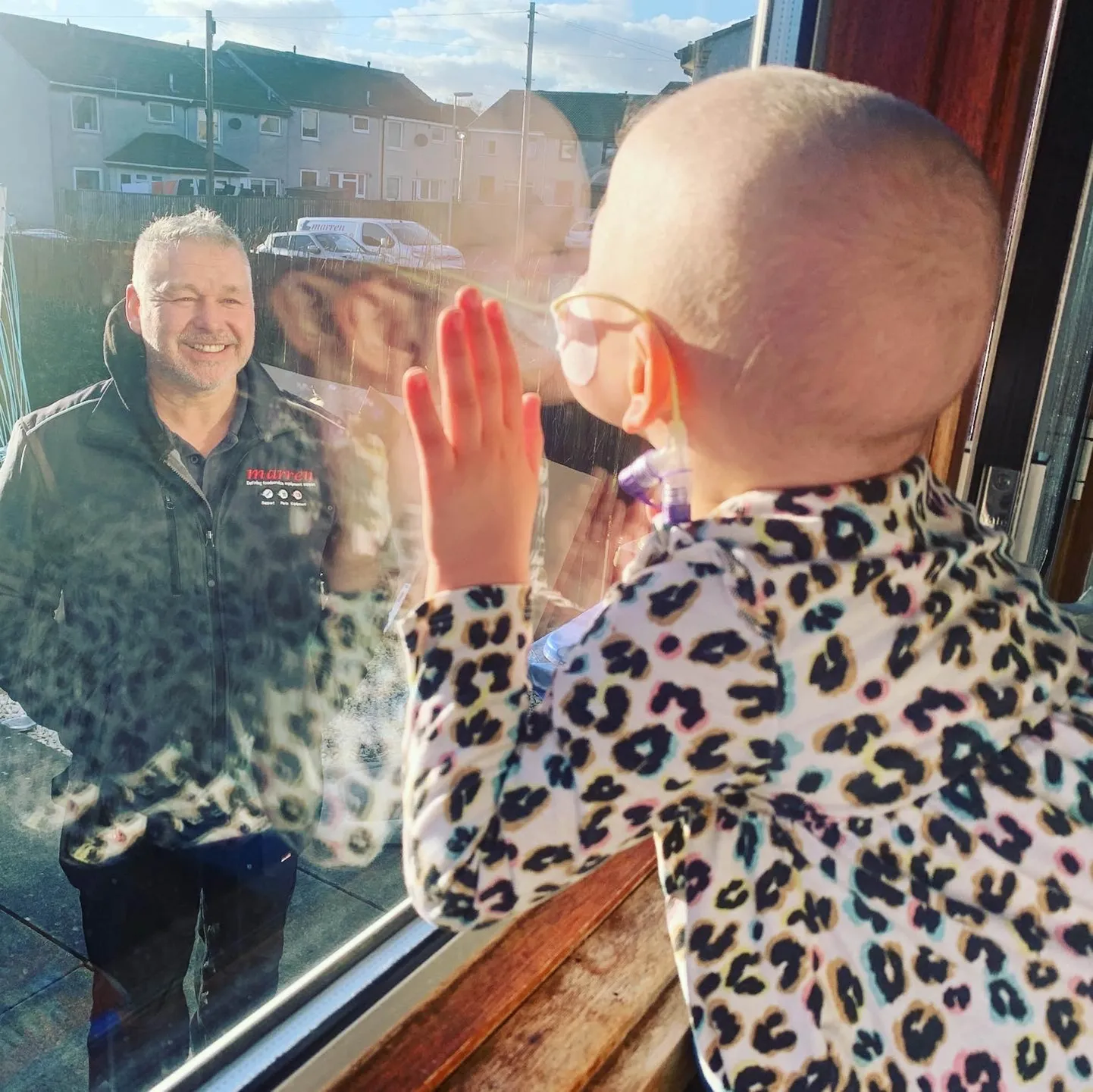 Мила целует окно, за которым стоит ее папа.