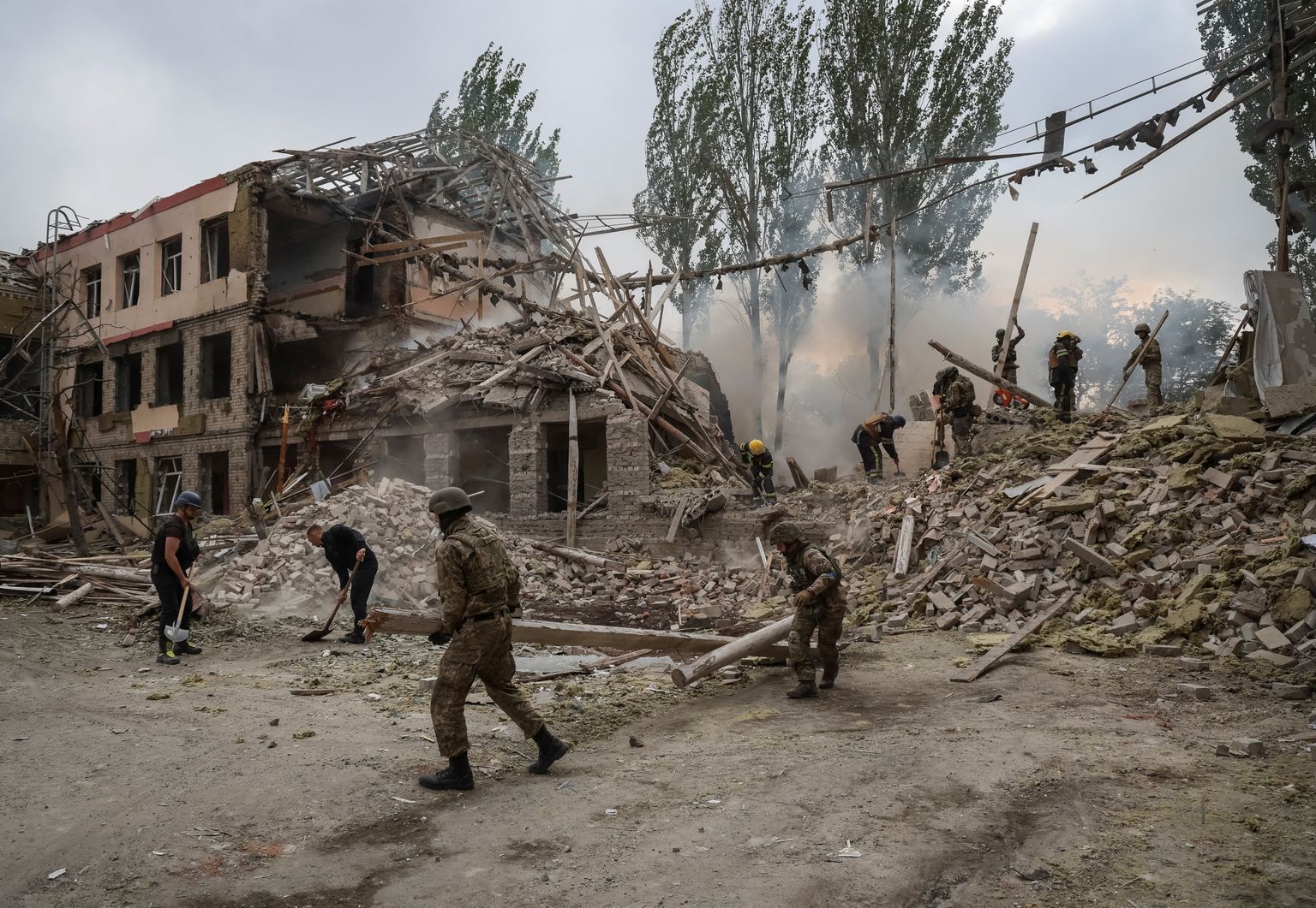 Спасатели и военнослужащие работают в здании школы, пострадавшем в результате российского военного удара. Краматорск, Донецкая область, Украина. 21 июля 2022 года.